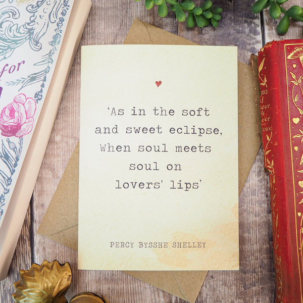 Card with a quote by Percy Bysshe Shelley on a wooden surface with books and stationery.